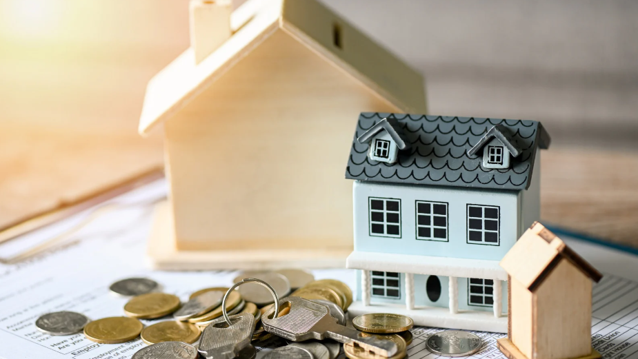 Miniature houses with coins on financial documents, symbolising real estate investment