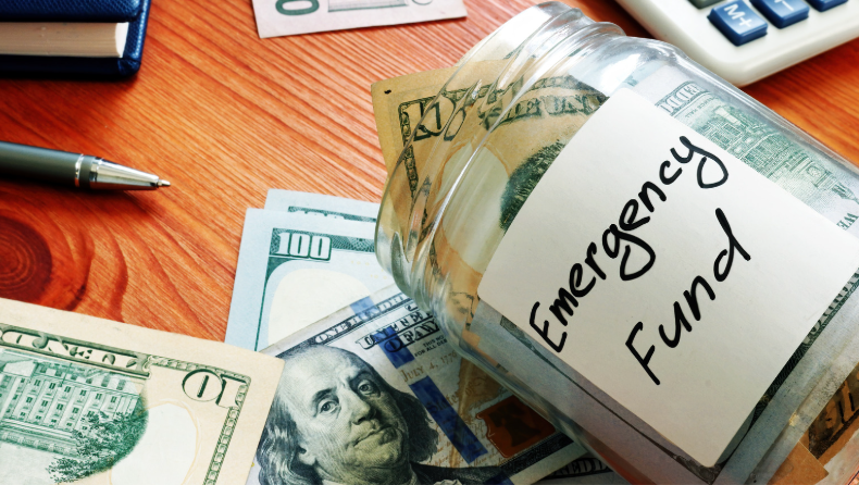 Glass jar labeled 'Emergency Fund' filled with U.S. hundred-dollar bills