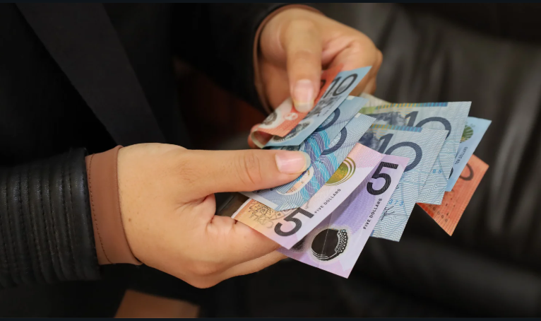 Person holding and counting Australian banknotes of various denominations