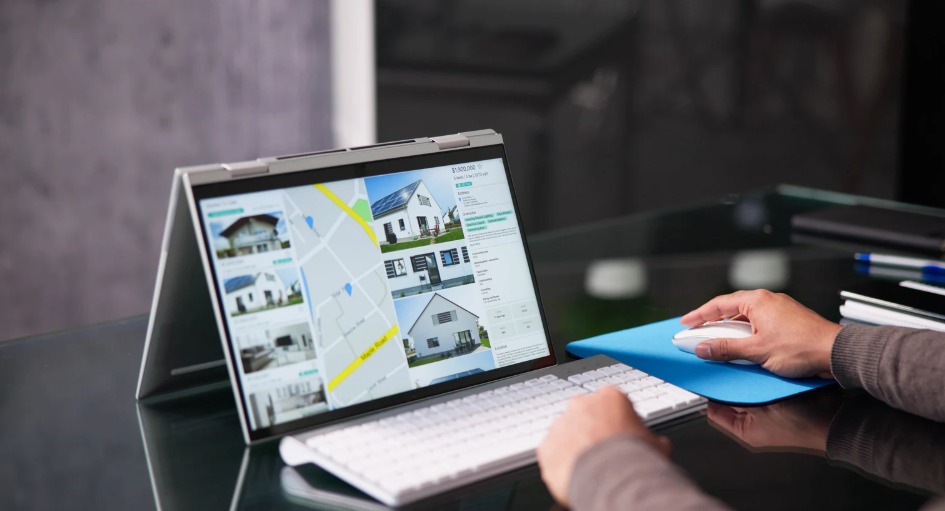 Person browsing property listings and a map on a convertible laptop