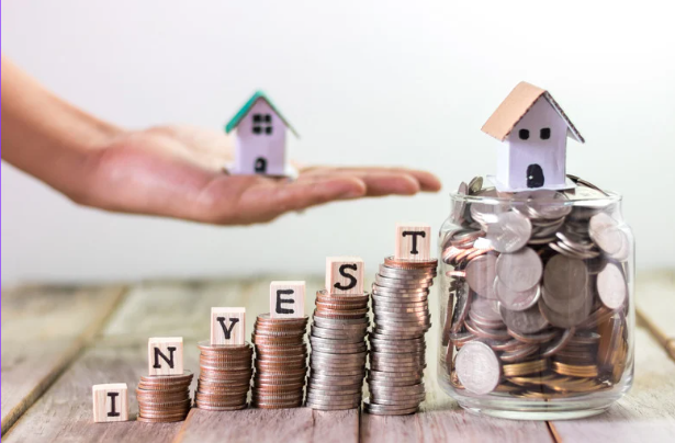 Stacked coins spelling INVEST, a jar of coins with a small house on top, and a hand holding another house.