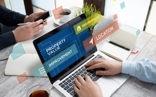 People are working on a laptop with real estate terms like property value, location, and neighborhood on the screen.