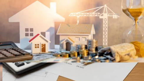 A calculator, coins, and miniature houses symbolize real estate investment and financial planning for property development.