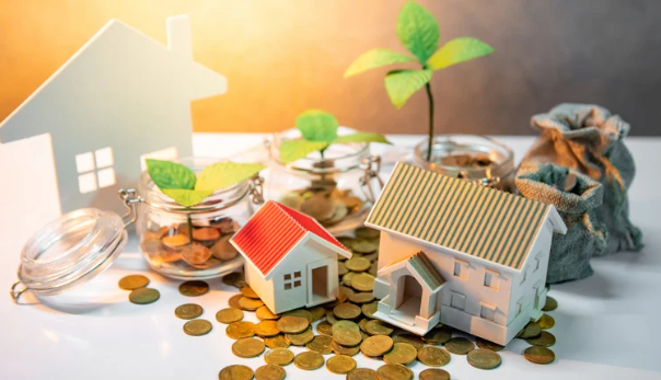A small model house next to a larger one, surrounded by coins and jars with coins and leaves, symbolizing investment and growth.