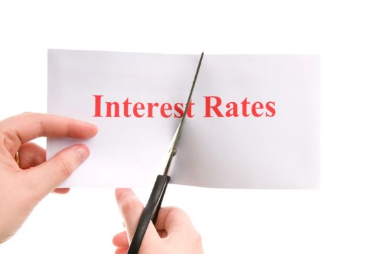 A person using scissors to cut a paper with the bold red text "Interest Rates," symbolizing a reduction in rates.