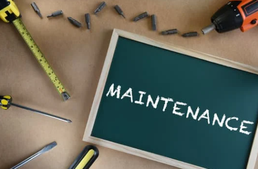 Maintenance concept with tools including screwdriver, drill, tape measure, and chalkboard with 'MAINTENANCE' text on workbench background