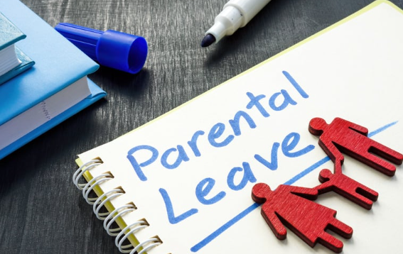 Notebook with text 'Parental Leave' beside wooden figures of parents and child, symbolizing family support and employee benefits.