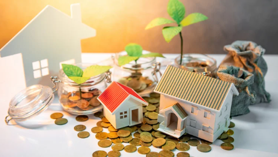 Miniature houses and glass jars with coins and growing plants symbolising property investment and financial growth