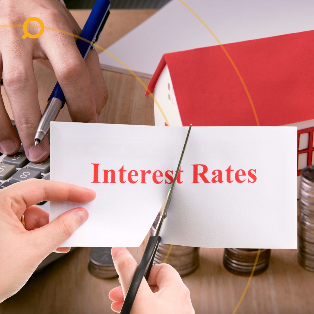Person cutting paper with the words Interest Rates next to house model and calculator