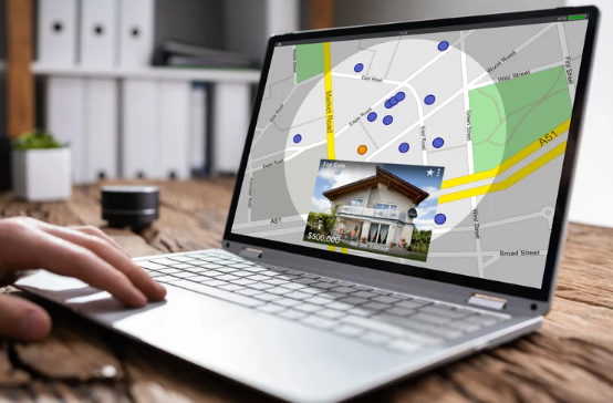 Person using a laptop displaying a real estate map with property listings, highlighting locations for sale or rent.