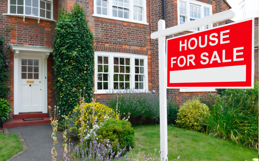 : Residential house with red For Sale sign in front yard, representing property sales and real estate investment opportunities.