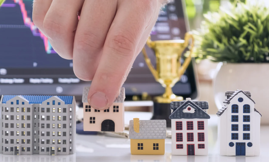 Hand picking miniature house model among different properties, symbolising real estate investment and property selection."