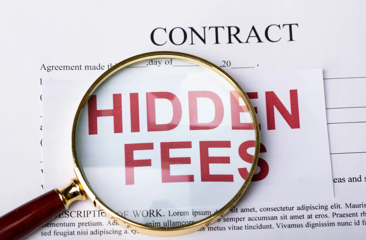 Magnifying glass highlighting “hidden fees” text written on a contract