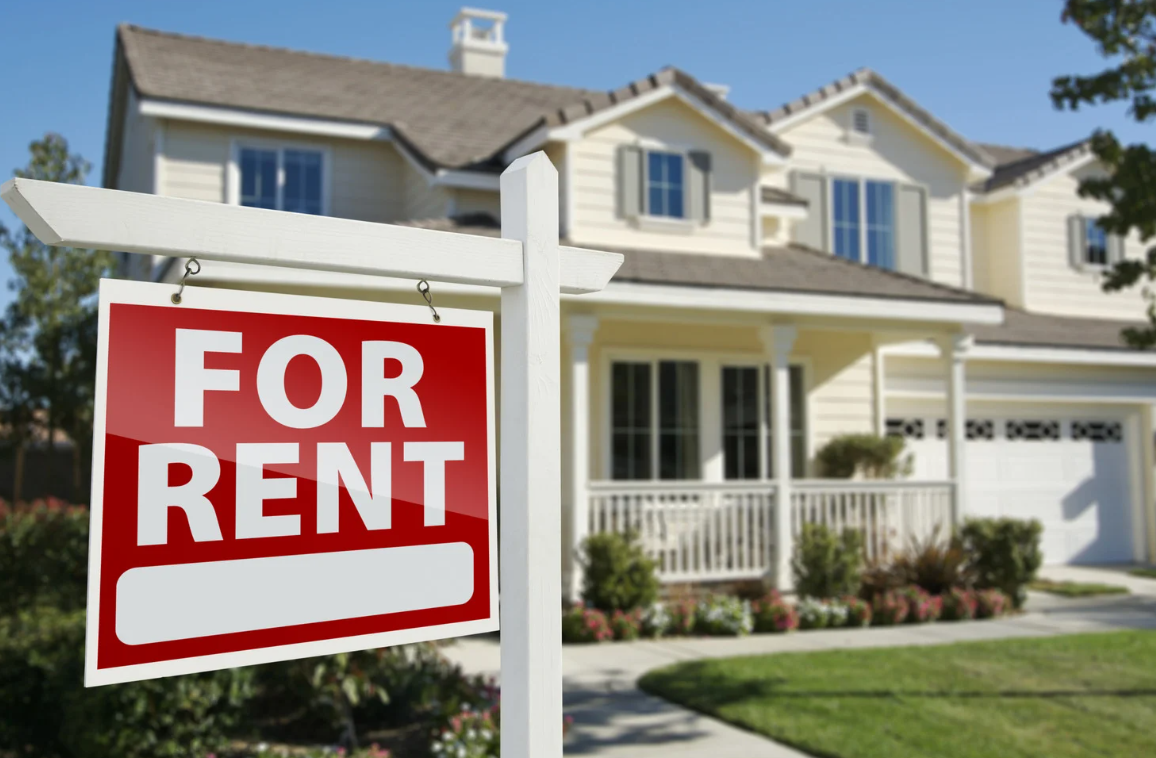 a house with a red sign that says “for rent”