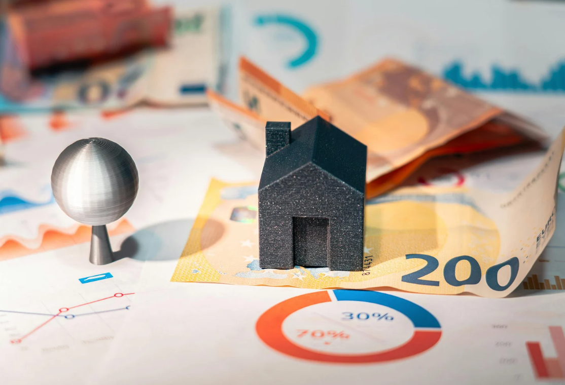Black miniature house standing on a $200 bill along with property investment data
