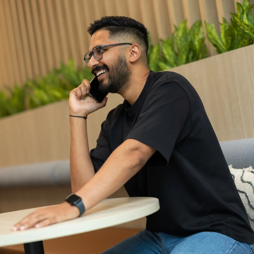 A man sitting at a table talking on a cell phone
