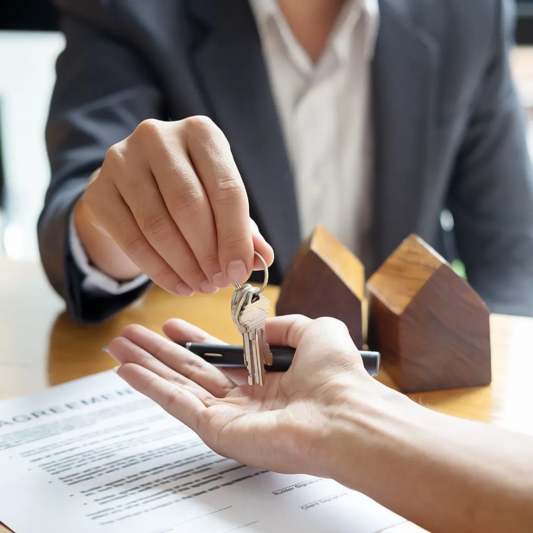 A person handing a house key to another person.