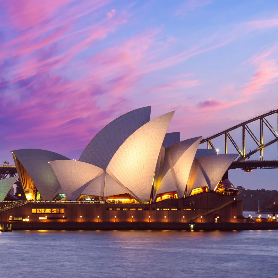 The sydney opera house is lit up at dusk.