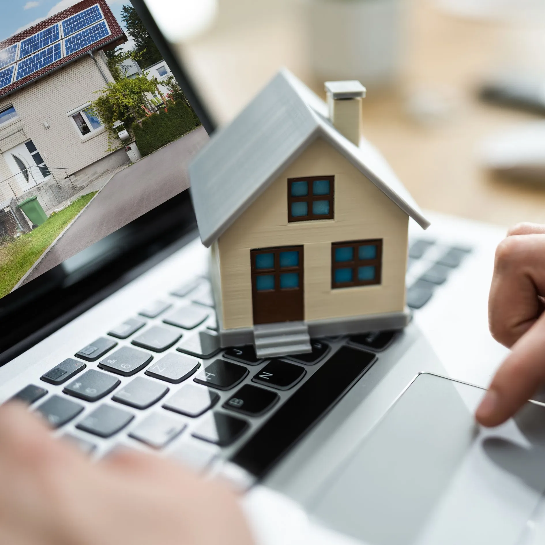 A person using a laptop with a house on the screen.