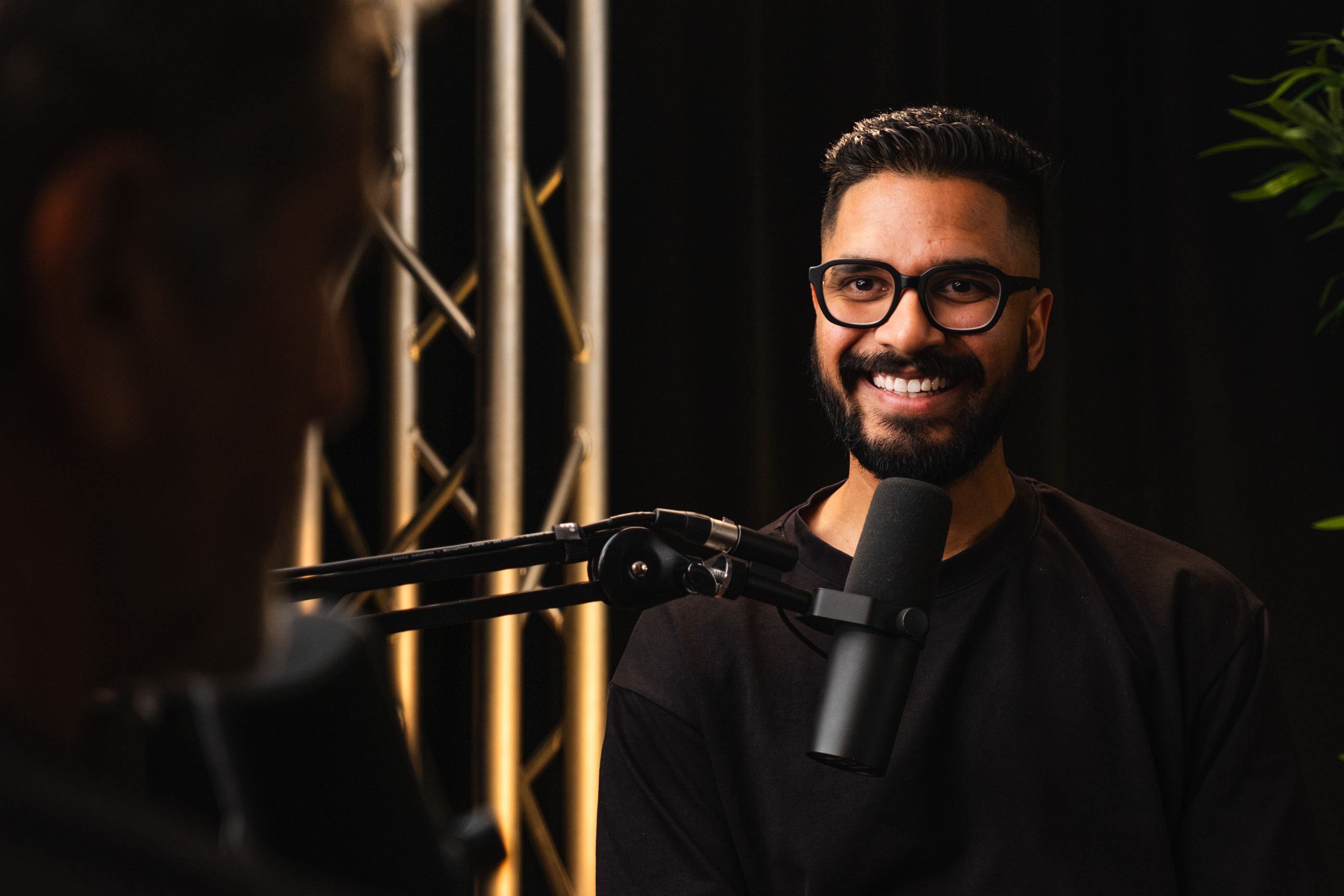 A man with glasses is talking into a microphone.