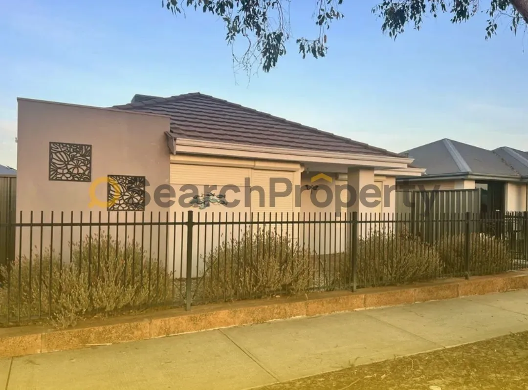 Modern single-storey home with roller shutters, decorative wall art, and a secure front fence, captured at sunset in a quiet suburban street.