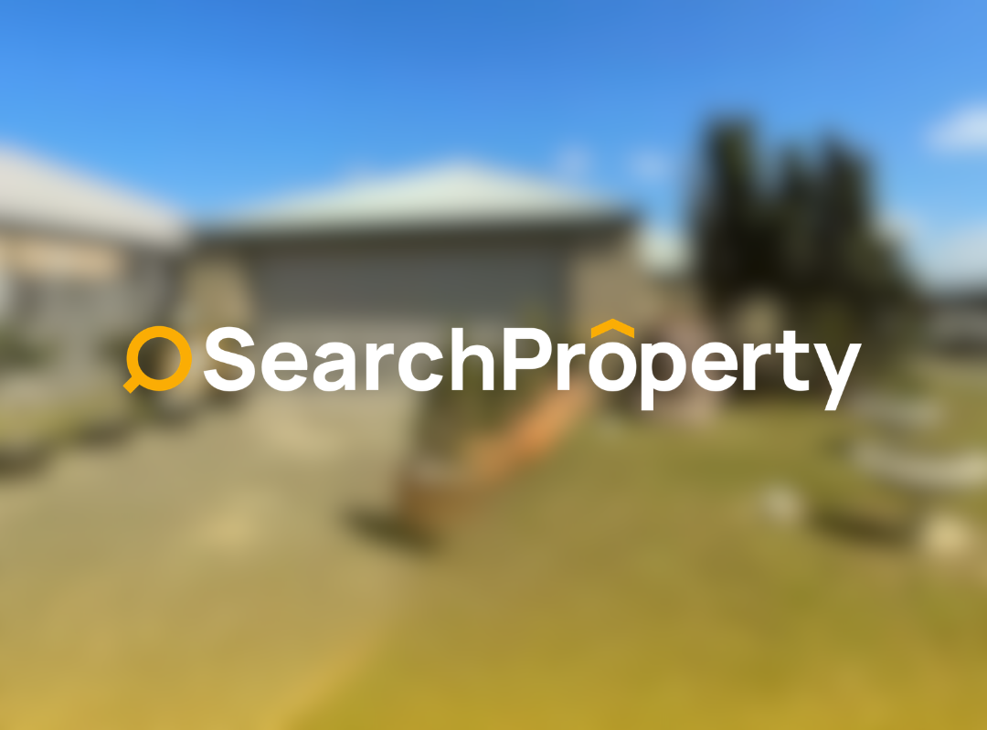 Front view of a sold 4-bedroom house with double garage and real estate sign on lawn under a clear blue sky.